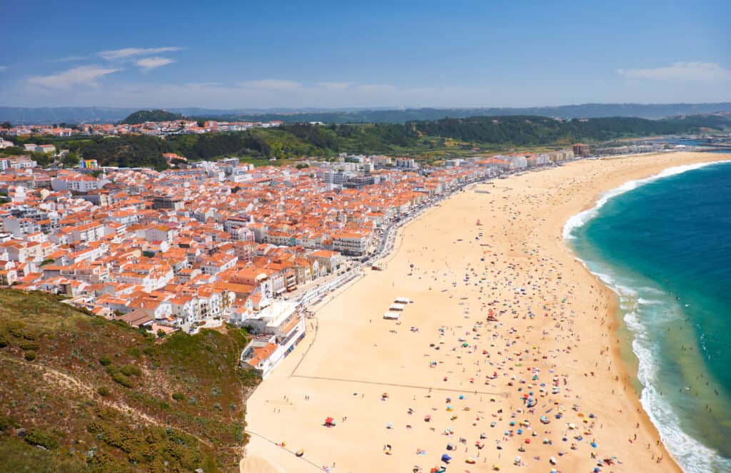 Bird's-eye view on Nazare beach riviera on the coast of Atlantic ocean with Nazare town. Portugal