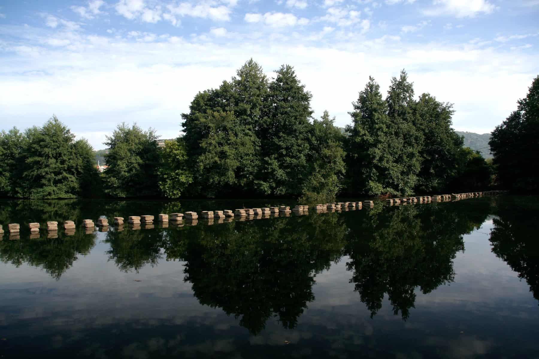 A row of stones and tree reflection in water CHAVES